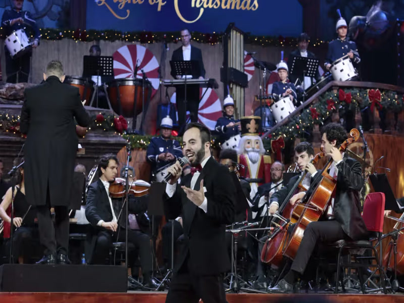Maestro rege a orquestra enquanto um cantor se apresenta em concerto de Natal — Natal Luz In Concert